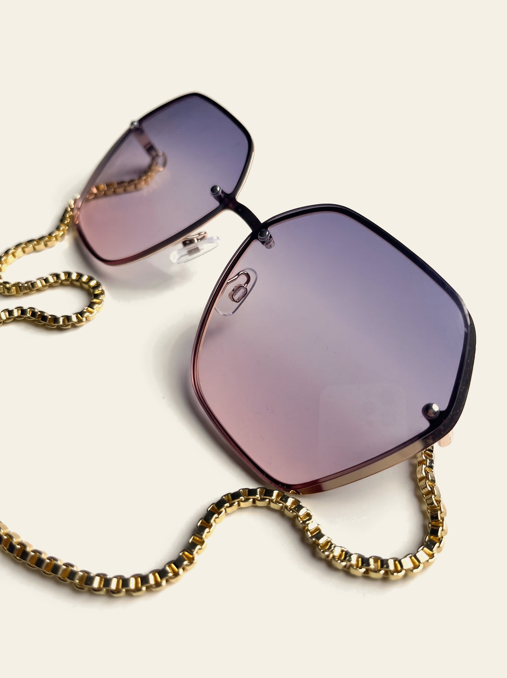 The Positano - front view of grey-pink gradient hexagon lenses with the gold chain draped below