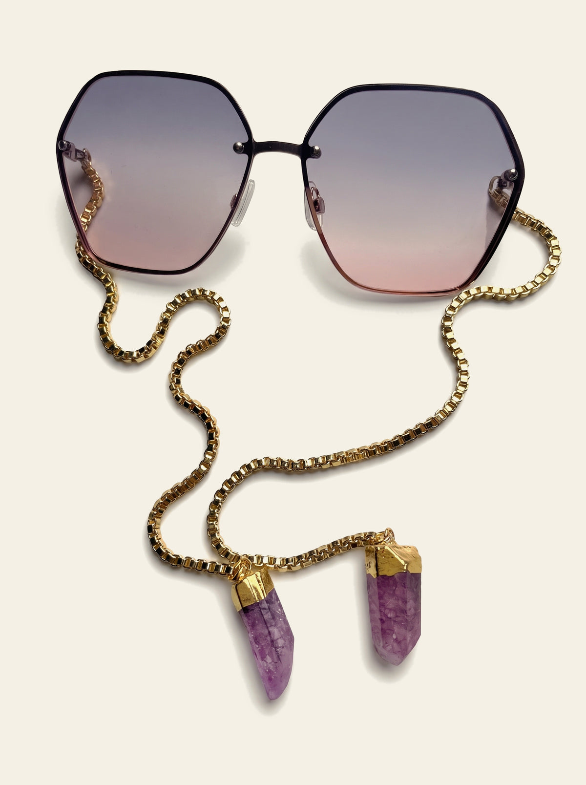 The Positano - top view of rimless hexagon lenses fading from grey-mauve to rose pink, gold box chain beneath