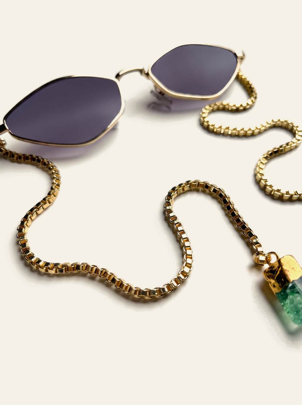 The Sorrento - close-up of the purple-grey gradient lens in a thin gold diamond rim with the gold box chain attached