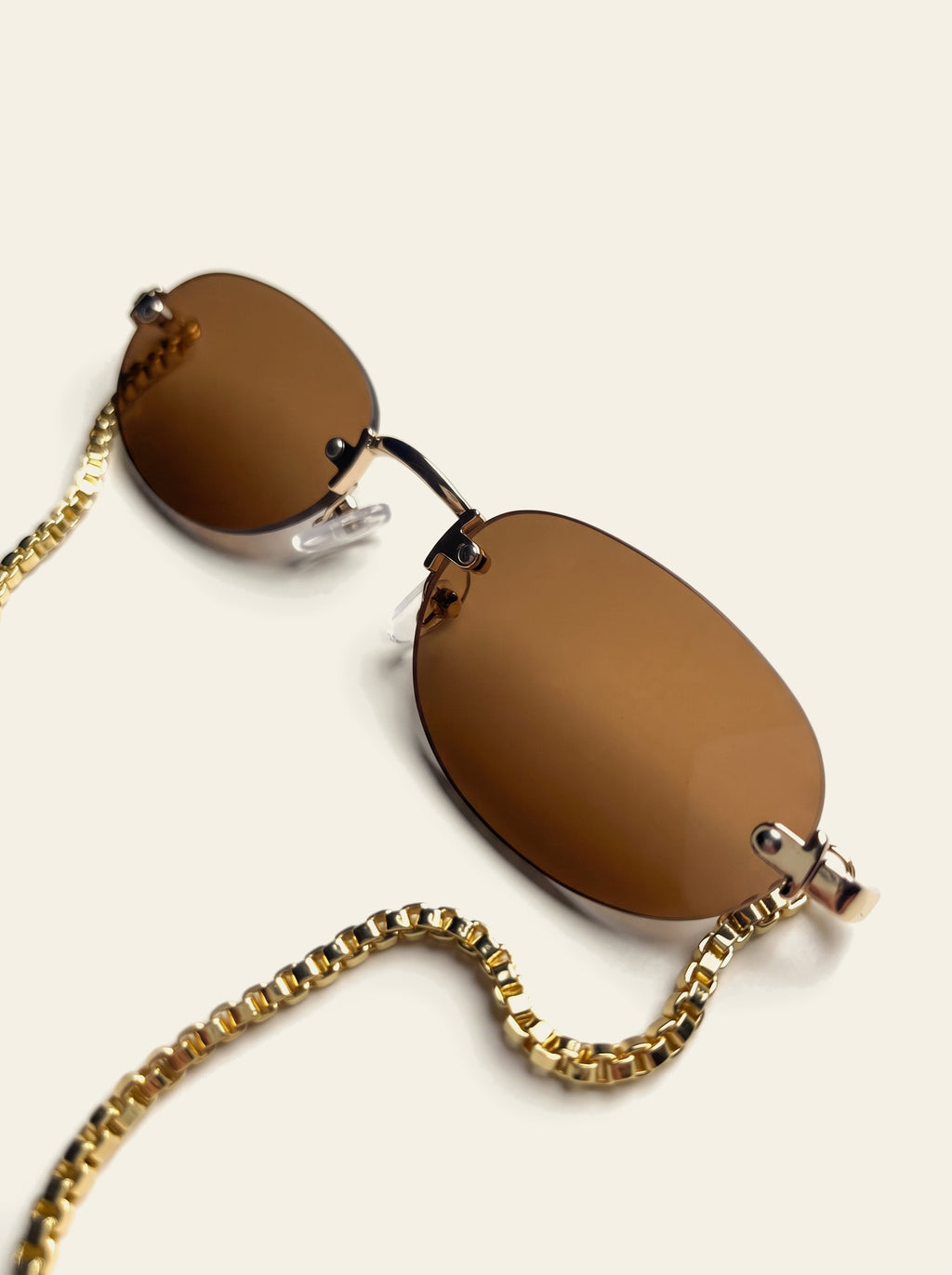 The Ischia - close-up of a solid amber-brown rimless oval lens with bevelled edge and gold end piece