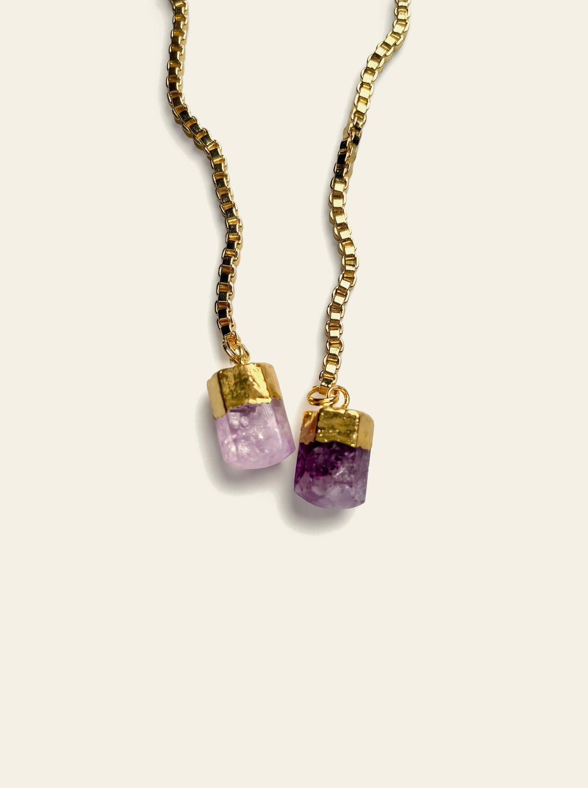 The Ischia - close-up of two raw purple quartz stones, one pale lilac and one deep violet, hand-set in gold-plated caps on a gold box chain