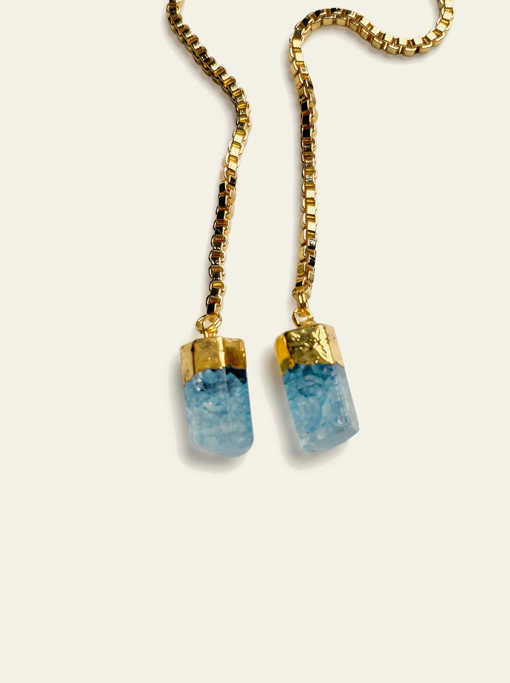 The Como - close-up of two raw pale blue quartz stones hand-set in gold-dipped caps on gold box chains