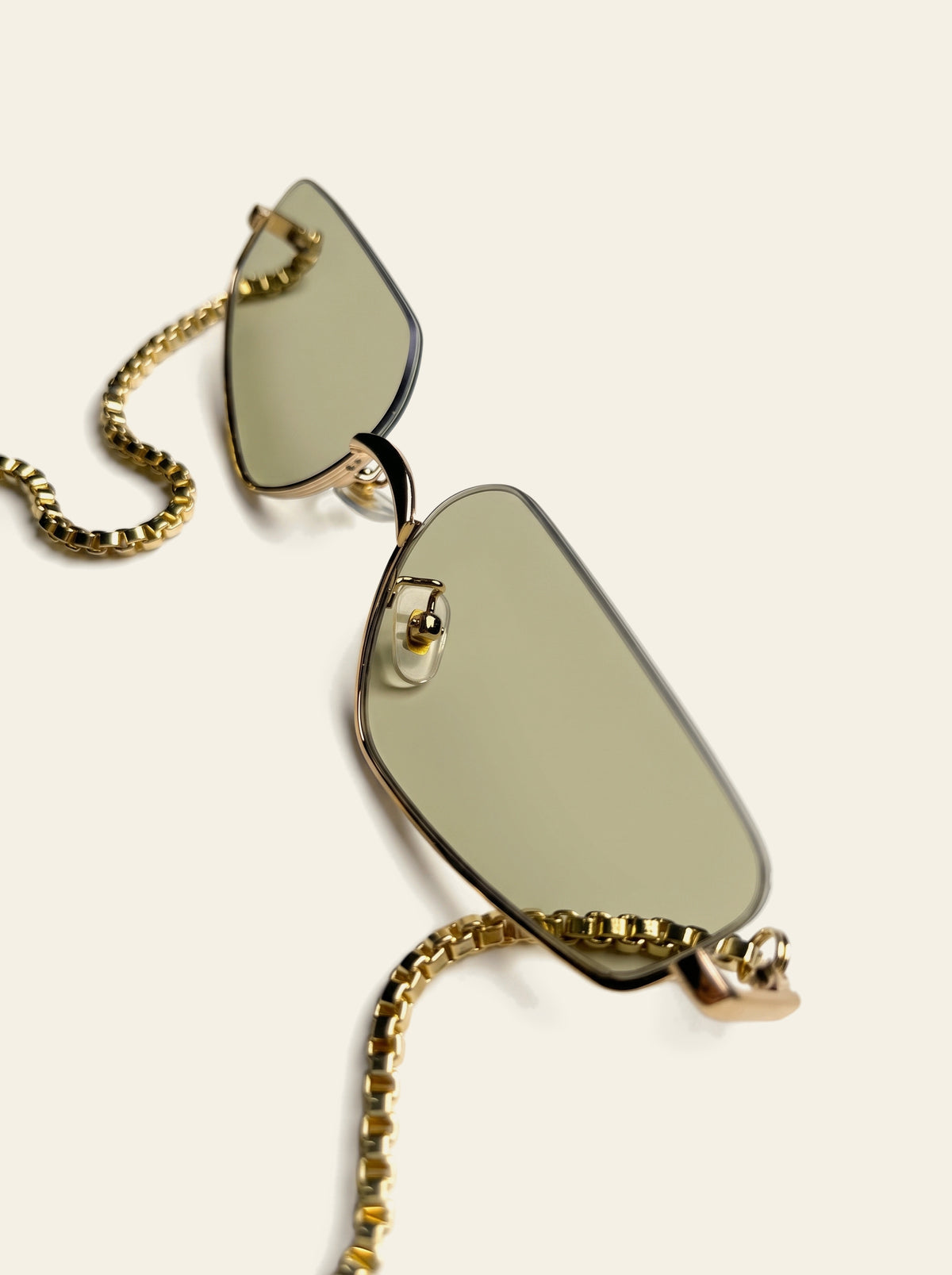 The Antibes - close-up of the pale green rimless lenses and slim gold bridge with the gold chain falling from each corner