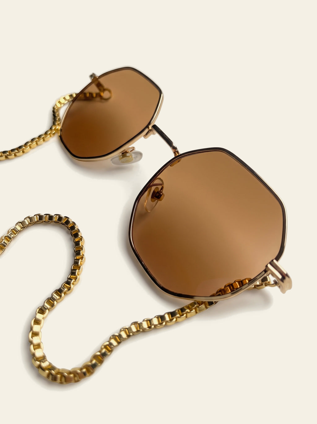 The Sanremo - close-up of the eight-sided gold wire rim and solid warm brown polycarbonate lens with the box chain alongside