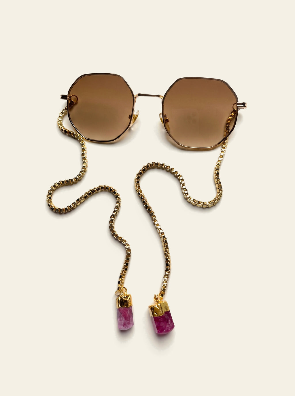 The Sanremo - gold octagon frame with brown lenses laid flat, 18K gold-plated box chain draped to two pink quartz stones, top view