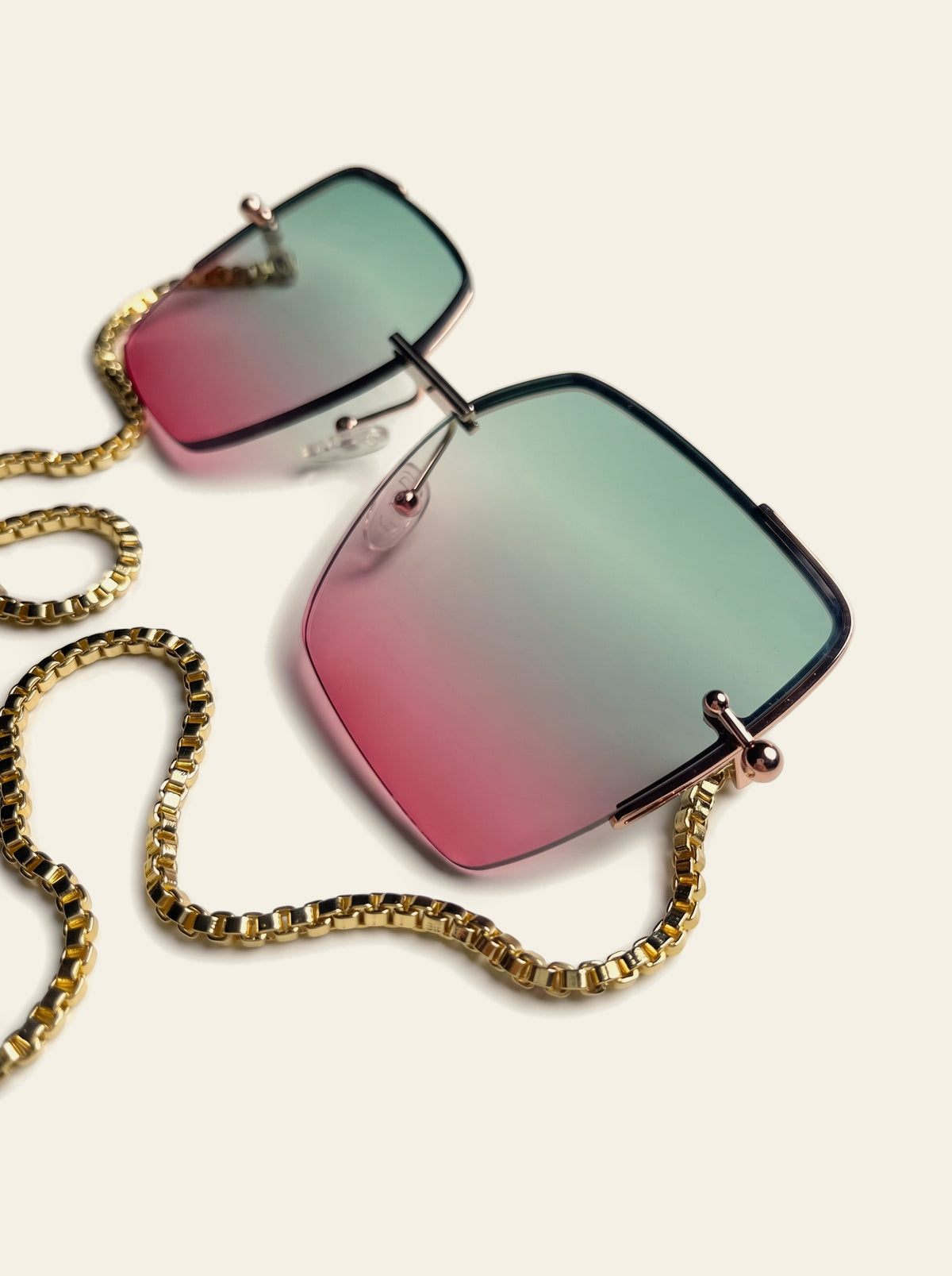 The Marbella - close-up of green-to-pink gradient lens, hairline gold brow bar and clear nose pad, with gold box chain