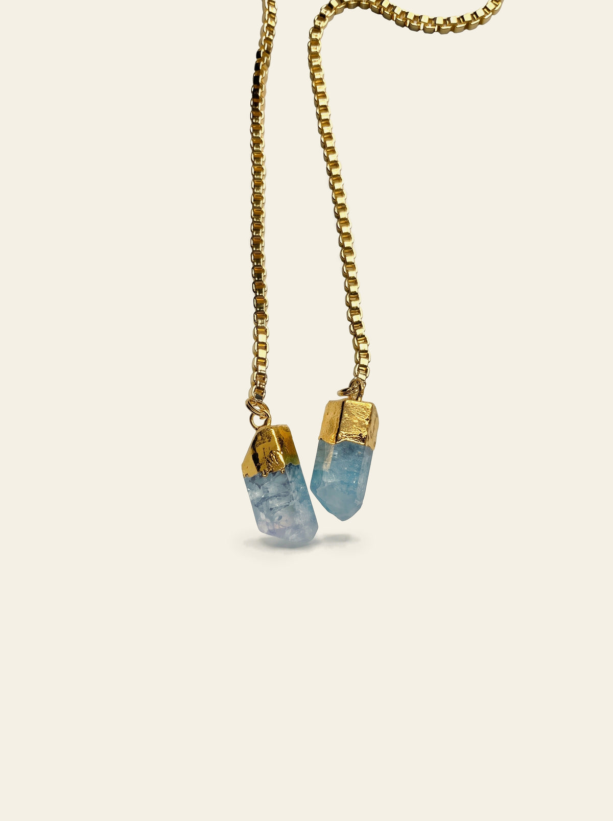 The Cassis - close-up of two raw pale blue quartz stones hand-set in gold caps on the gold box chain