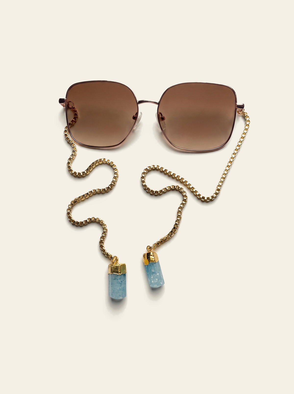 The Menton - top view of square gold-finished sunglasses with brown gradient lenses and gold box chain