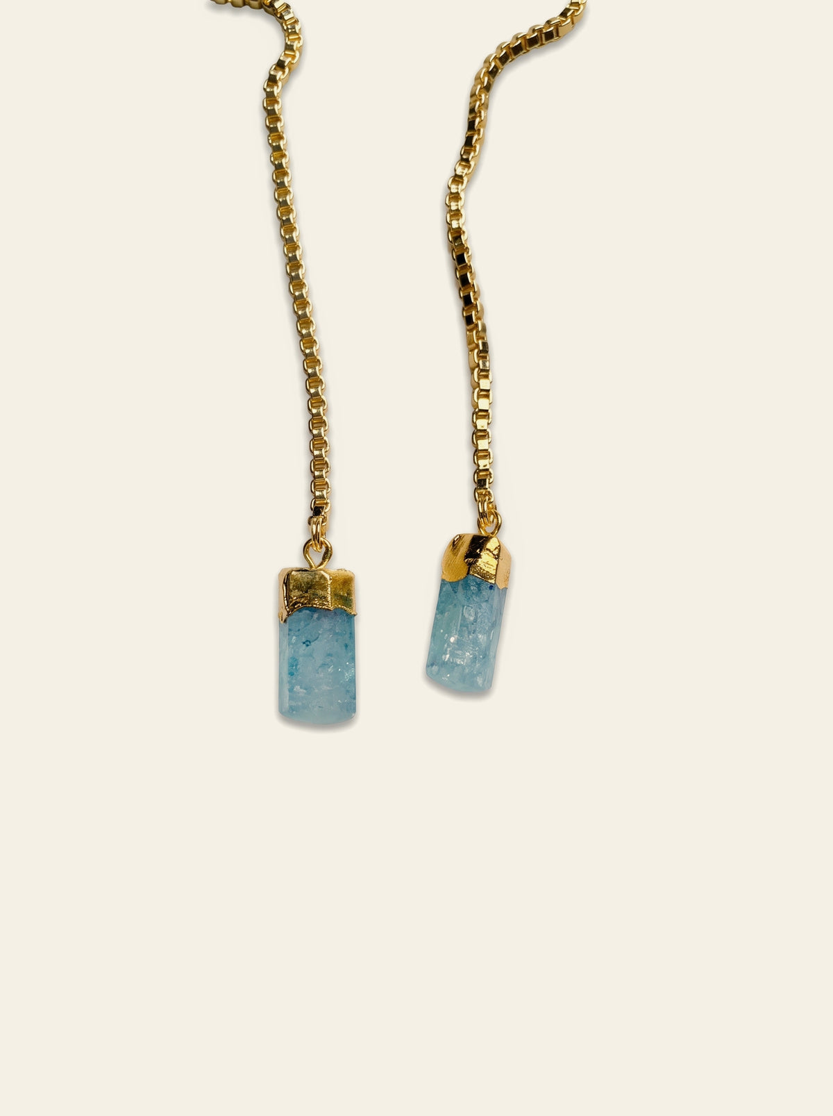 The Menton - close-up of two raw pale blue quartz stones hand-set in gold-plated caps on a gold box chain
