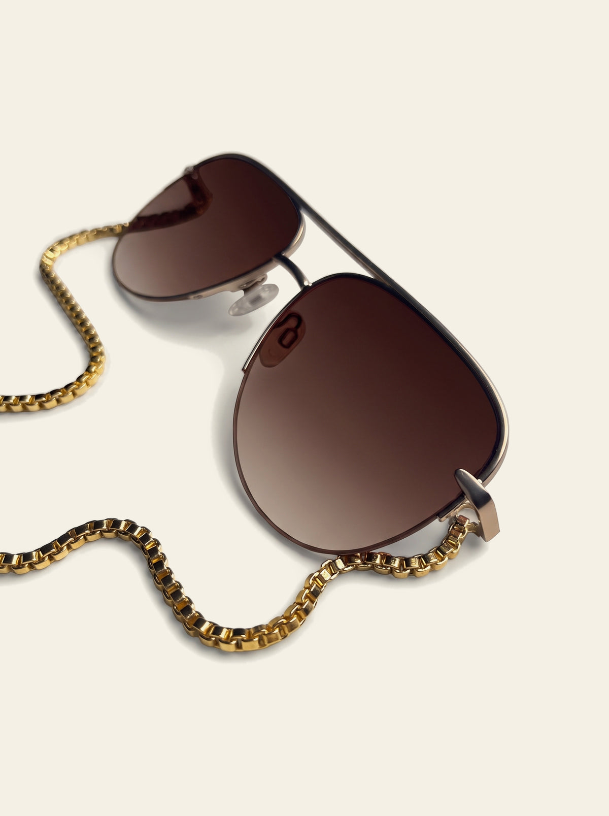 The Camogli - front view of gold aviator sunglasses with brown gradient lenses, double bridge and open lower rim, gold chain looped below