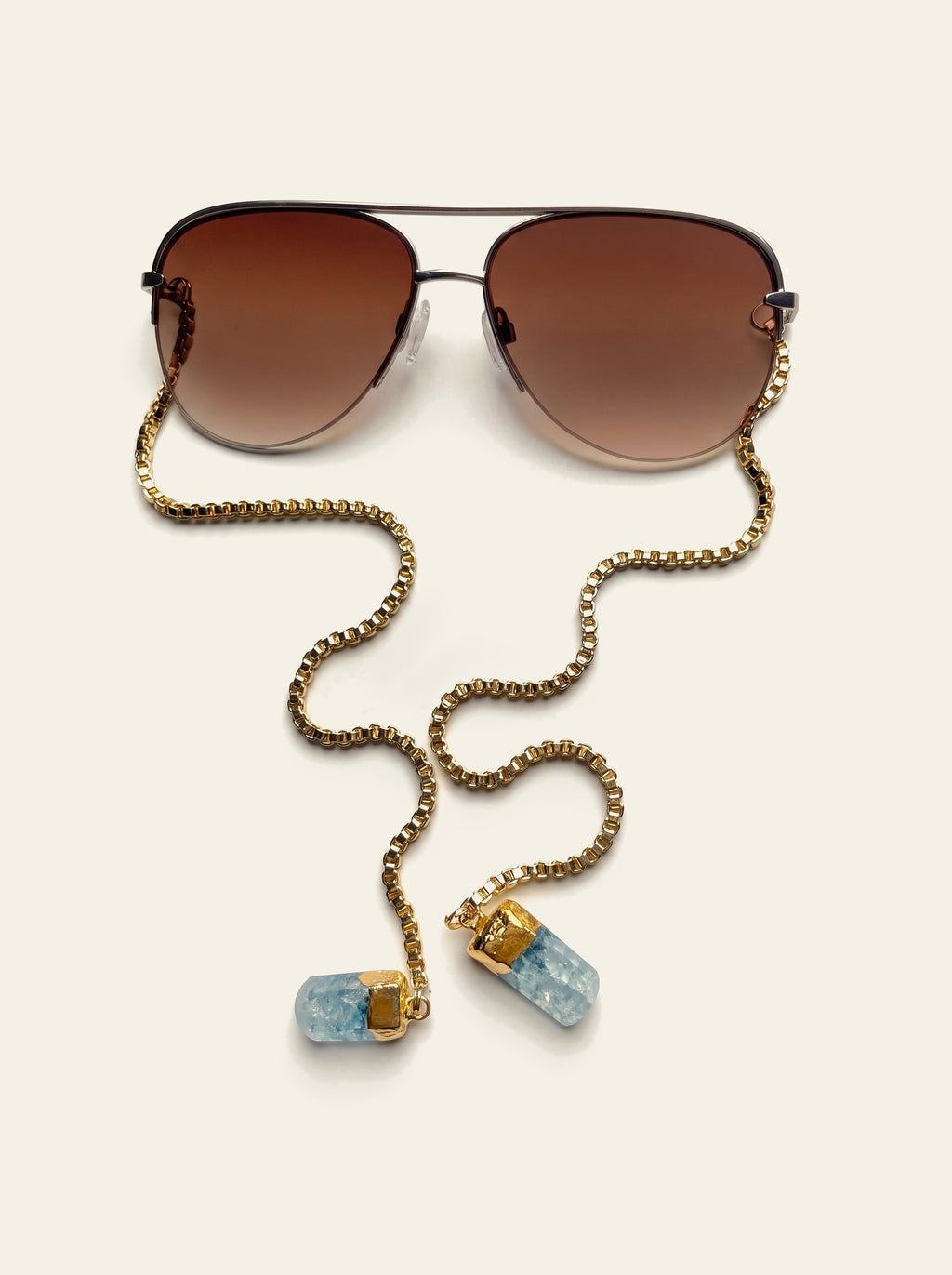 The Camogli - close view from above of a gold semi-rimless aviator frame with brown gradient lenses and a gold box chain