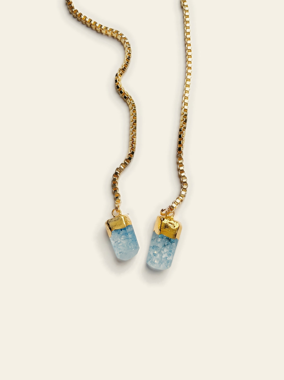 The Camogli - close-up of two raw pale blue quartz stones hand-set in gold caps at the ends of a gold box chain