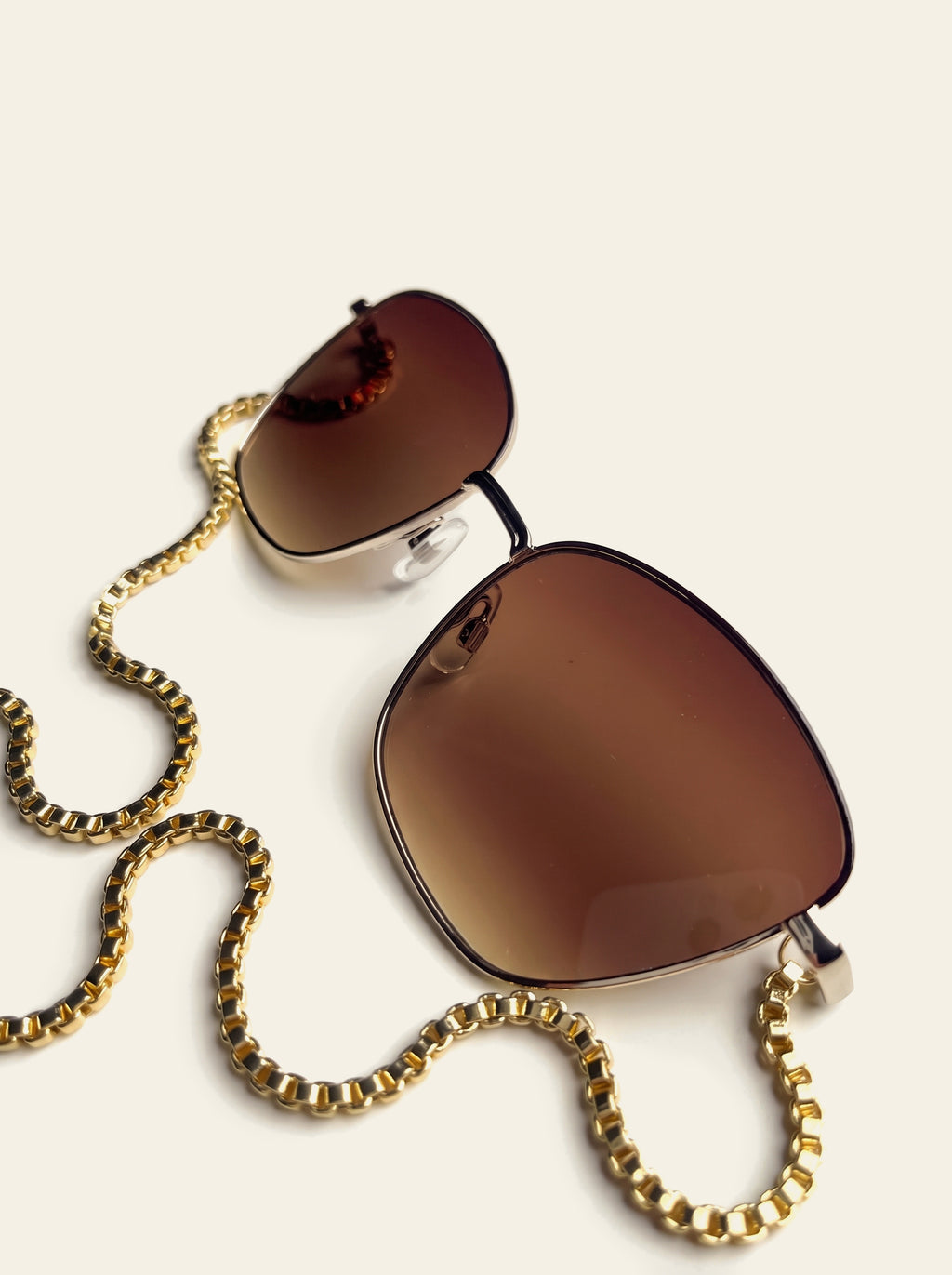 The Biarritz - front view of the gold semi-rimless butterfly frame with brown gradient lenses, gold chain hanging to two blue quartz stones