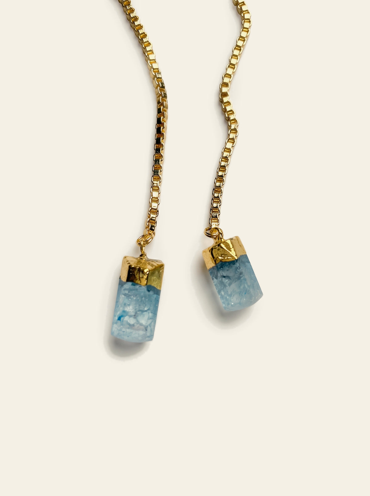 The Biarritz - close-up of two raw pale blue quartz stones hand-set in gold caps on a gold box chain