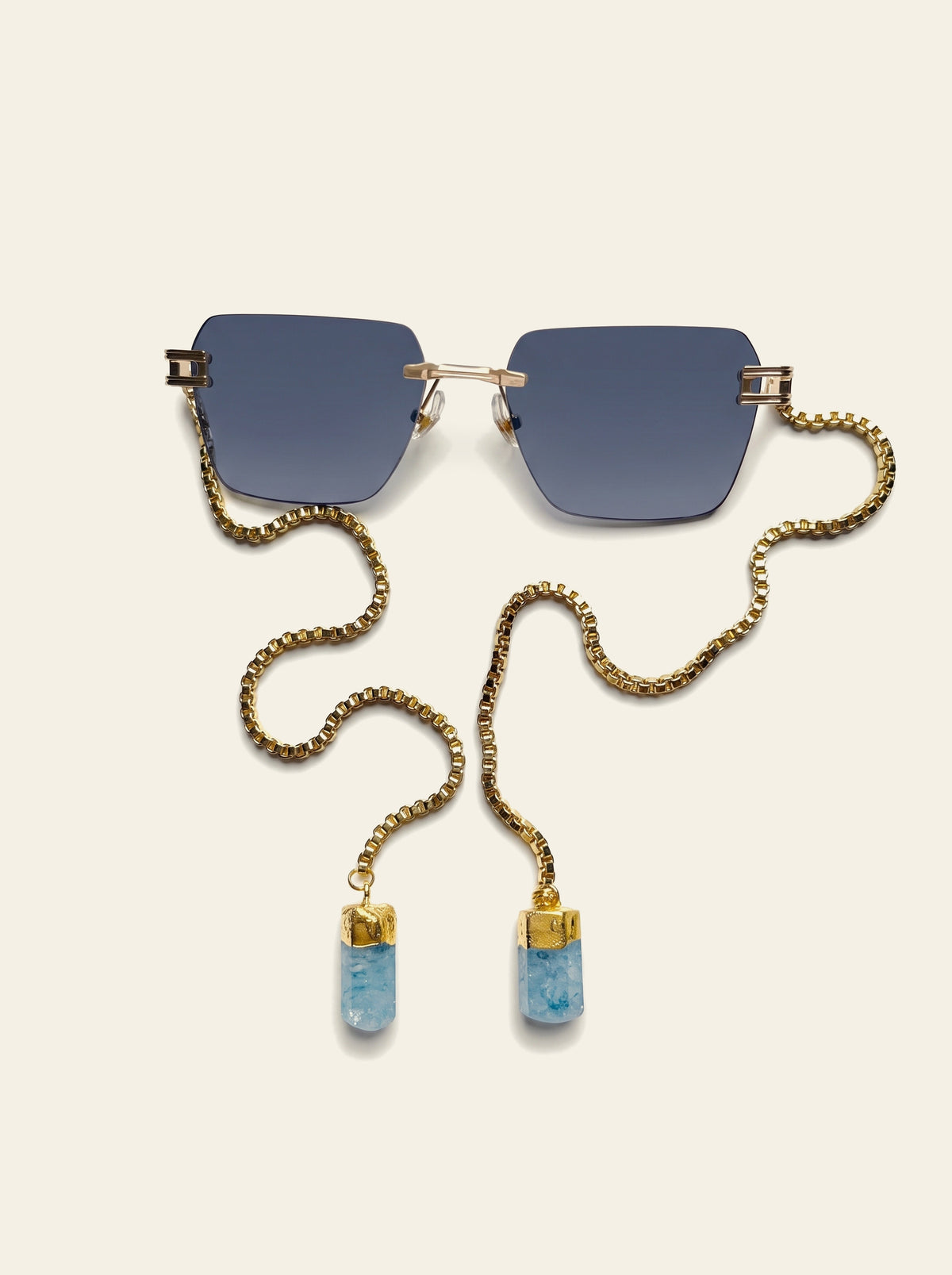 The Sardinia - top view of rimless square gold frame with dark ink-blue lenses and gold box chain