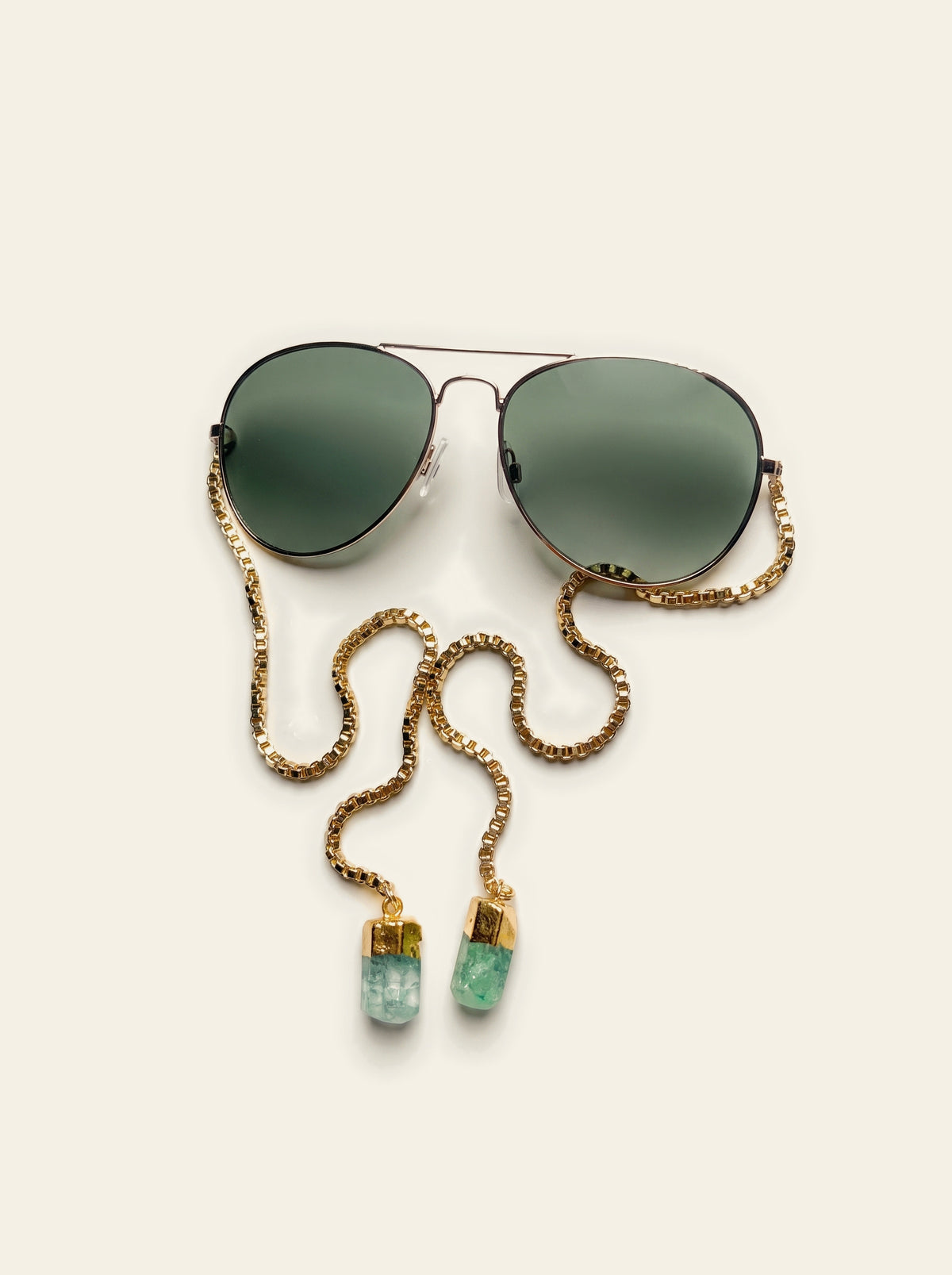 The Saint-Tropez - top view of gold aviator sunglasses with solid dark green lenses and a coiled gold box chain