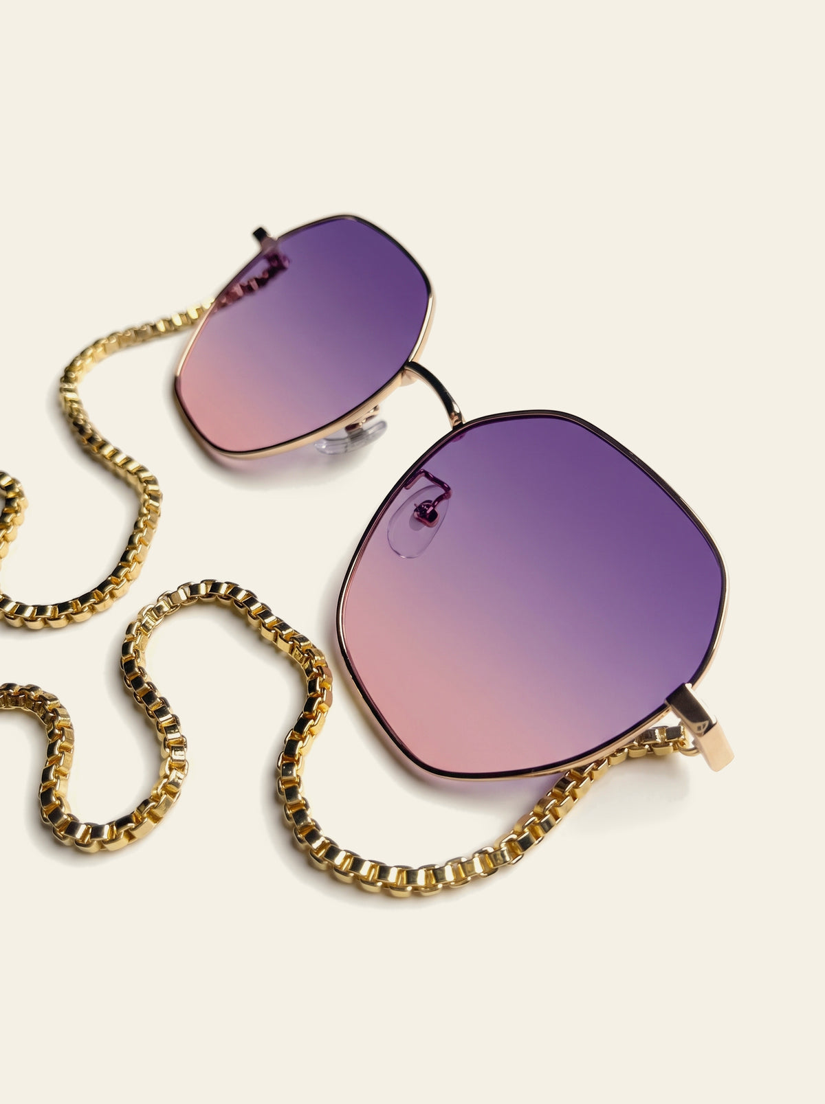 The Lipari - flat lay of thin gold hexagon frame with purple-pink gradient lenses, chain looped below with purple quartz stones