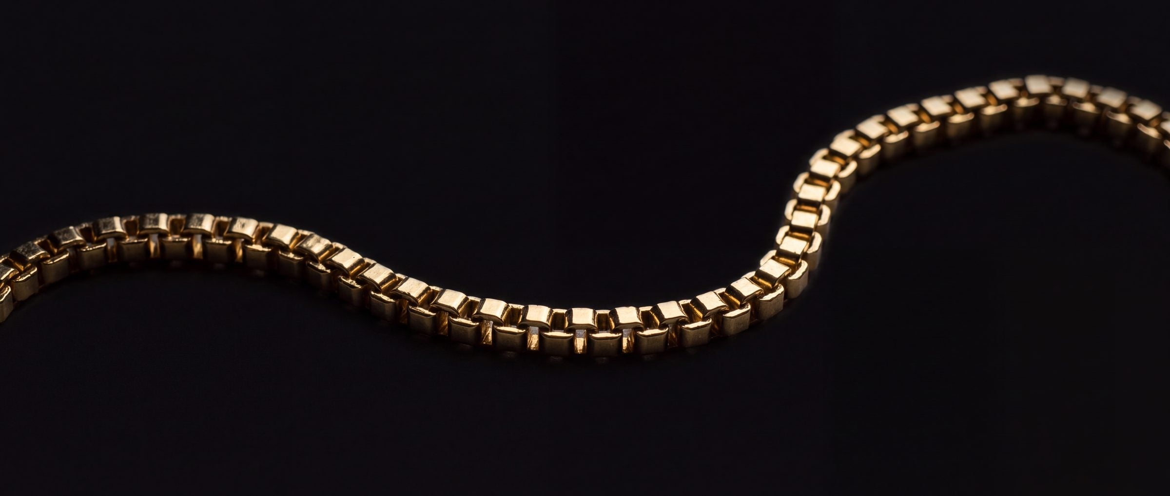 A length of gold box chain on black
